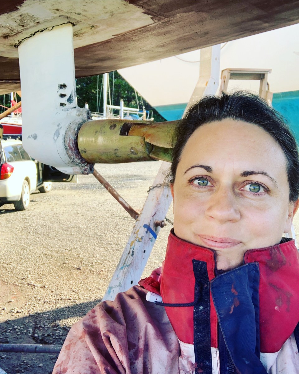 Woman standing under a yacht in haulout yard with propspeed coated propellor