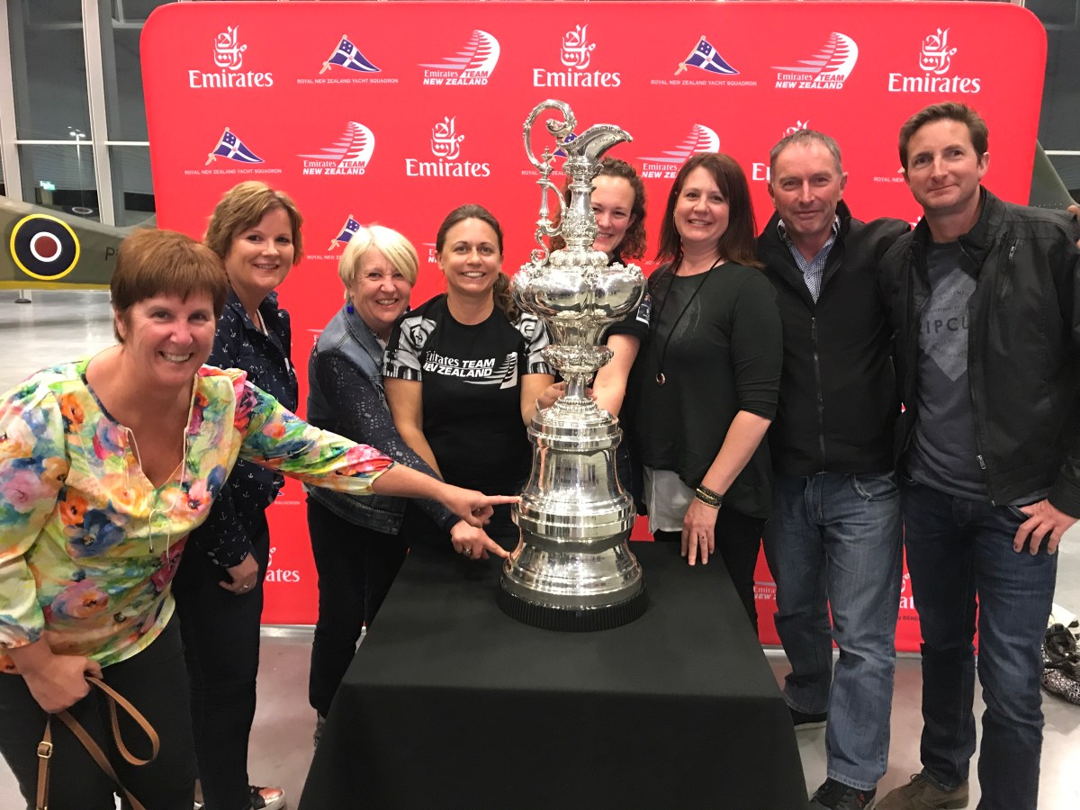 A group of friends surrounding the Americas Cup
